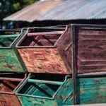 Stacked weathered metal bins with a rustic look against a corrugated backdrop outdoors.