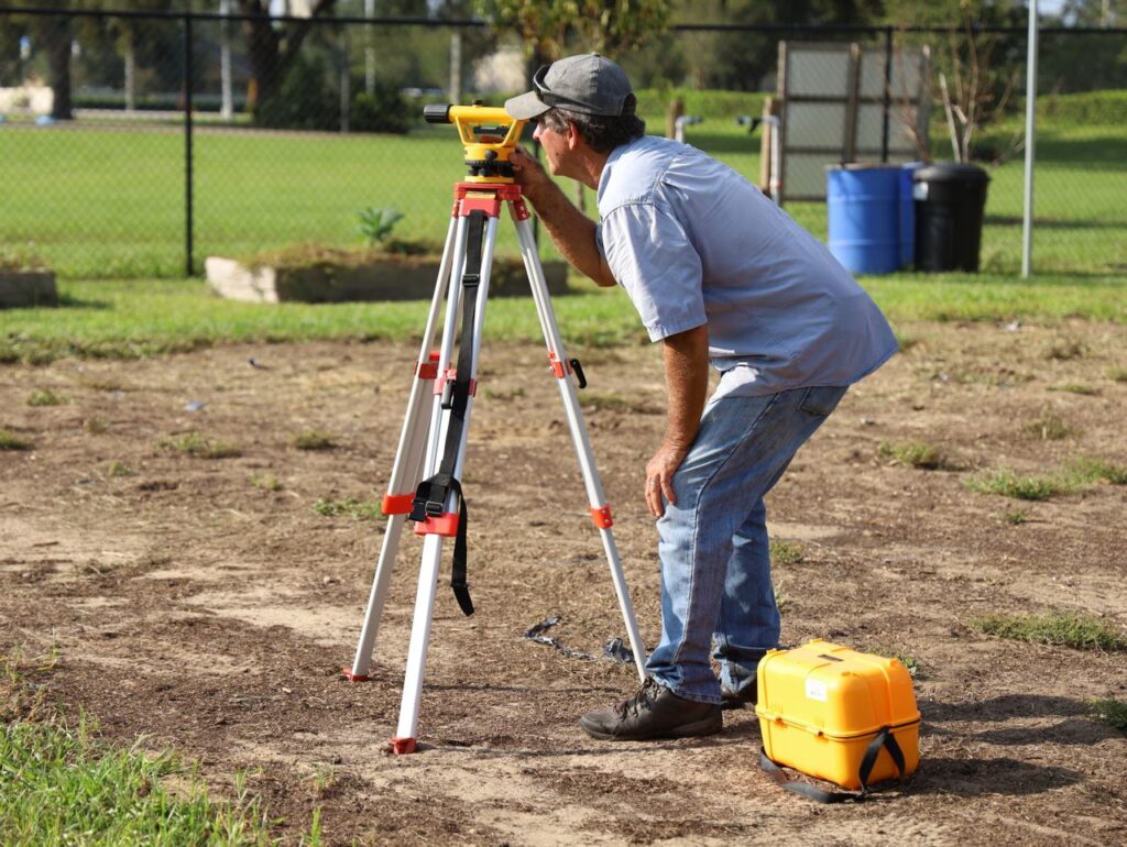 A land surveyor at work using equipment on a field in Tavares, Florida.